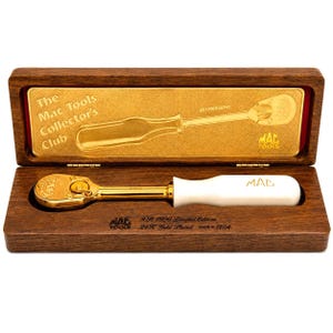 May include: A 24K gold-plated Mac Tools XR 1990 limited edition ratchet with a white handle, presented in a wooden display box. The gold-toned interior lid features the text The Mac Tools Collector's Club and XR 1990 Ratchet with the Mac Tools logo.