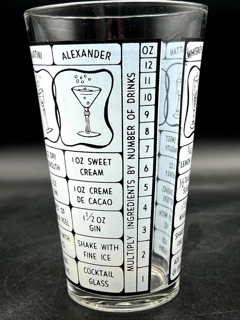 May include: A clear cocktail shaker glass with a black and white design. The glass features cocktail recipes, including the "Alexander" cocktail, and a scale for measuring ingredients. The text includes measurements in ounces.