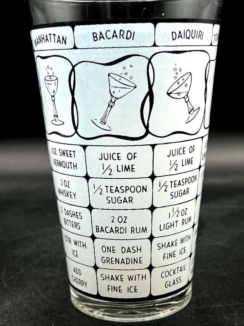 May include: A vintage cocktail shaker with a black and white design. The shaker features recipes for Manhattan, Bacardi, and Daiquiri cocktails, including ingredient measurements in ounces and teaspoons. The glass has a black rim and a clear base.