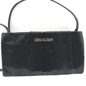 May include: Black rectangular handbag with a snakeskin pattern. The bag has a long strap and a silver "MICHAEL KORS" logo. The bag is made of a textured material and has a glossy finish.
