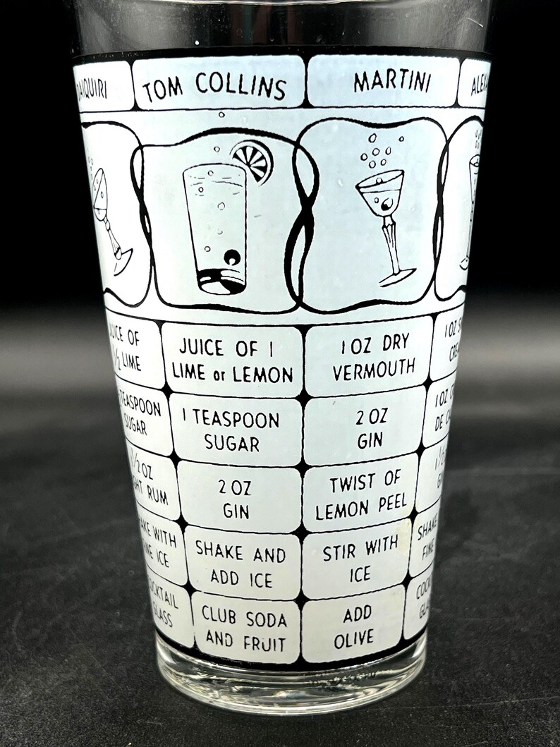 May include: A vintage cocktail shaker with a black and white design. The shaker features recipes for classic cocktails like Tom Collins and Martini, with ingredient measurements and instructions. The glass is clear.