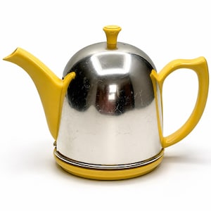 May include: A teapot featuring a polished silver-tone metal body with a bright yellow handle, spout, lid knob, and base. The dome-shaped lid sits atop the rounded metallic vessel, which is complemented by the vibrant yellow accents throughout.