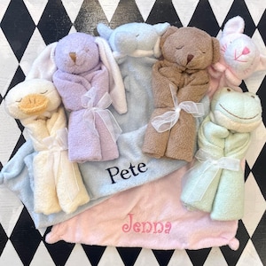 May include: A collection of plush animal security blankets featuring a yellow duck, purple rabbit, blue elephant, brown bear, pink cat, and green frog. Each plush toy is attached to a soft blanket, with the names Pete and Jenna embroidered in blue and pink.
