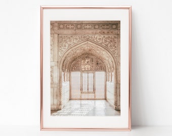 May include: A framed photograph of a white marble archway with intricate carvings and a large, ornate wooden door with a grid pattern. Sunlight streams through the door, casting shadows on the floor.