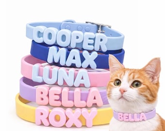 Puede incluir: Una pila de coloridos collares para gatos con nombres en letras en relieve: COOPER, MAX, LUNA, BELLA y ROXY. Los collares son azules, azul marino, rosas, lavanda y amarillos. Un gato jengibre lleva un collar lavanda que dice BELLA.