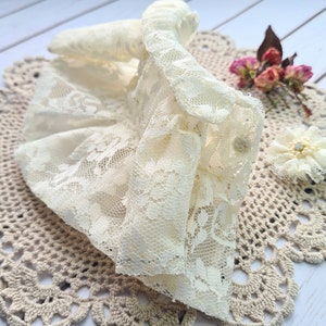 Könnte beinhalten: Ein zartes weißes Spitzenkragen mit Rüschen, auf einem gehäkelten Untersetzer präsentiert.