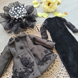 May include: A black and white polka dot hat with a black lace trim, a black dress with lace sleeves, and a black and white patterned jacket with black lace trim.