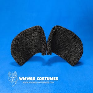 Puede incluir: Orejas de disfraz negras y texturizadas sobre un fondo azul. Las orejas están hechas de un material similar a una malla. El texto "WMW66 COSTUMES" y una dirección web son visibles.