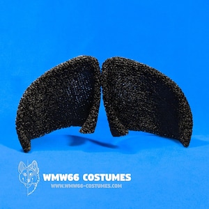 May include: A pair of black costume ears with a textured surface, set against a bright blue background. The ears are symmetrical and appear to be made of a dense material. The image includes the text "WMW66 COSTUMES" and a website address.