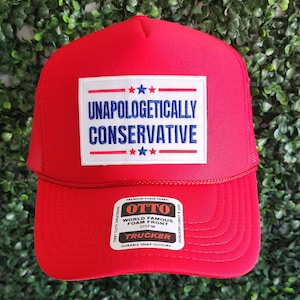 May include: Red trucker hat with a white patch that says "Unapologetically Conservative" in blue lettering. The hat has a black mesh back and a black snap closure.