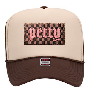 May include: A trucker hat with a brown brim and a tan front panel. The hat features a rectangular patch with a checkered pattern and the word "petty" in pink, gothic-style lettering. The hat has a brown mesh back.
