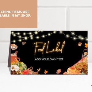 May include: A rectangular folded card with a black background featuring string lights at the top, autumn-themed watercolor illustrations of pumpkins, s'mores, and leaves, and the text Food Label and ADD YOUR OWN TEXT in a glowing orange font.