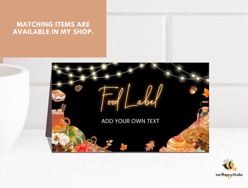 May include: A rectangular folded card with a black background featuring string lights at the top, autumn-themed watercolor illustrations of pumpkins, s'mores, and leaves, and the text Food Label and ADD YOUR OWN TEXT in a glowing orange font.