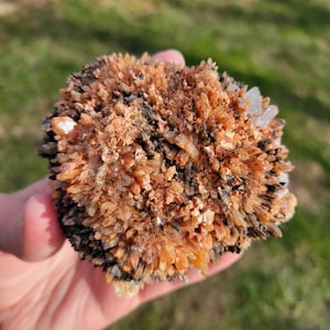 May include: A cluster of orange and brown crystals with a rough, textured surface. The crystals are densely packed together, creating a unique and interesting formation.