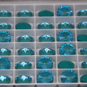 Pu&ograve; includere: Un vassoio pieno di strass color turchese. Gli strass sono di diverse forme, tra cui rotondi, ovali e a semicerchio. Il vassoio &egrave; diviso in piccoli scomparti quadrati, ognuno contenente un singolo strass. Gli strass hanno una superficie sfaccettata che riflette la luce.