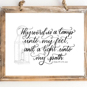 May include: Black and white printable wall art featuring a hand-lettered quote from Psalm 119:105, "Thy word is a lamp unto my feet, and a light unto my path." The quote is accompanied by a simple line drawing of a lantern.