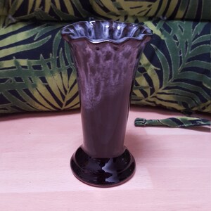 Könnte beinhalten: Eine schwarze und weiße Keramikvase mit geriffeltem Rand. Die Vase hat eine glänzende Oberfläche und eine weiße Glasur, die einen Marmoreffekt erzeugt.