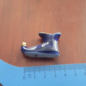 May include: A small blue and gold ceramic shoe figurine. The shoe is about 3 cm long and has a pointed toe. The figurine is made by Limoges France.