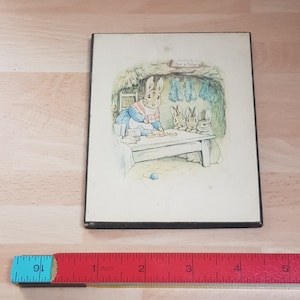 May include: A framed illustration of a mother rabbit and three baby rabbits sitting at a table with a blue teacup and a plate of biscuits. The illustration is titled "The Tale of Mrs. Tiggy-Winkle".