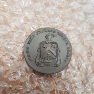 May include: A bronze medal with the inscription "Robert Mays Grammar School, Odiham" and a coat of arms with the date 1673.