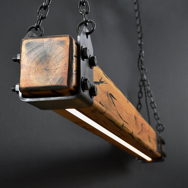 May include: A rustic wood and metal pendant light fixture with a long, rectangular wooden beam and a square wooden end cap. The light fixture has a black metal frame and a chain for hanging. The light fixture has a white LED light strip running down the center of the wooden beam.
