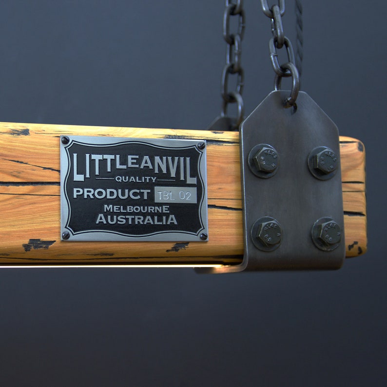 May include: A rustic wooden light fixture with a metal frame and chain. The fixture has a silver metal plaque with the text "LITTLEANVIL - QUALITY PRODUCT TBL 02 MELBOURNE AUSTRALIA".