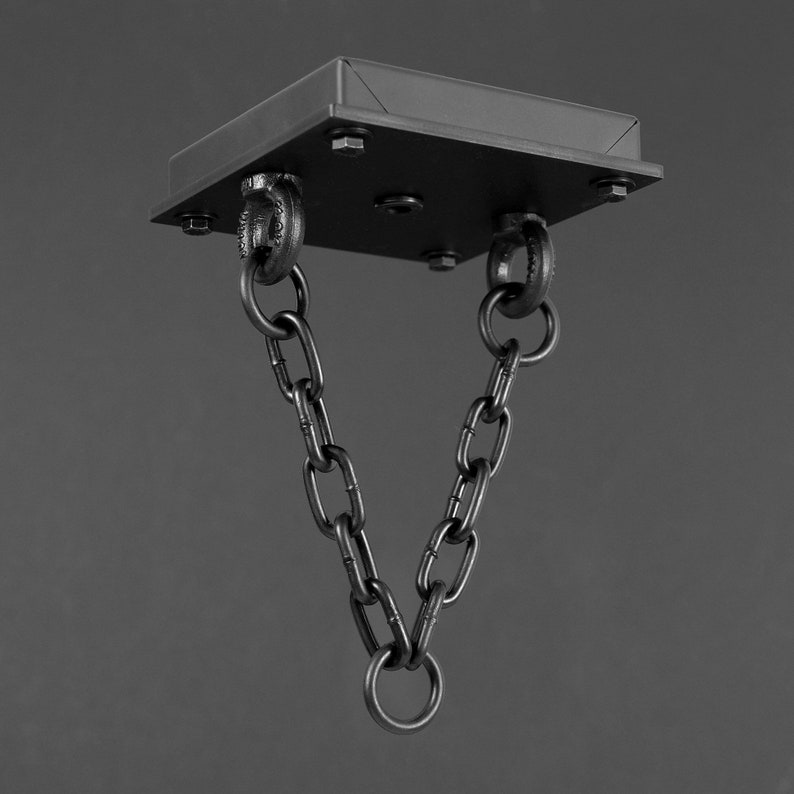 May include: Black metal ceiling plate with two chain links hanging down. The chains are connected at the bottom with a ring.