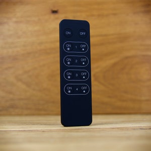 May include: Black remote control with four buttons labeled "ON" and "OFF" with a number from 1 to 4. Each button has a small asterisk symbol.