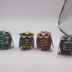 Può includere: Quattro piccole statuine di gufo in filo metallico. I gufi sono di diversi colori: verde, giallo, rosso e nero.