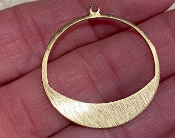 Puede incluir: Pendiente de círculo de metal dorado con acabado texturizado. El círculo tiene una sección recortada en la parte inferior, creando una forma de media luna.