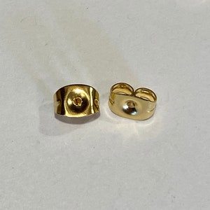 May include: A close-up of ten gold-colored earring backs. The backs are designed to be used with post earrings.