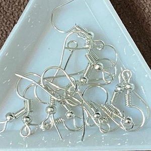 May include: A close-up of a group of silver earring hooks. The hooks are made of metal and have a spring-loaded closure. They are perfect for making your own earrings.