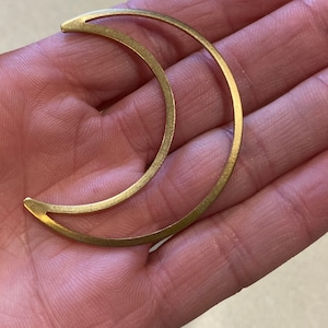 May include: A gold crescent moon shaped metal pendant.