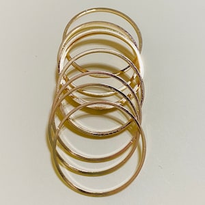 May include: A set of seven gold-toned stacking rings. The rings are all different sizes and are stacked on top of each other.