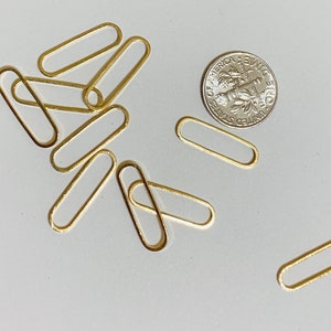 May include: A set of ten gold-toned metal oval-shaped rings. The rings are approximately 1 inch in length.