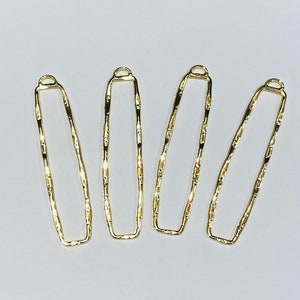 May include: Four gold-colored metal rectangular shapes with a textured surface. Each shape has a small loop at the top.