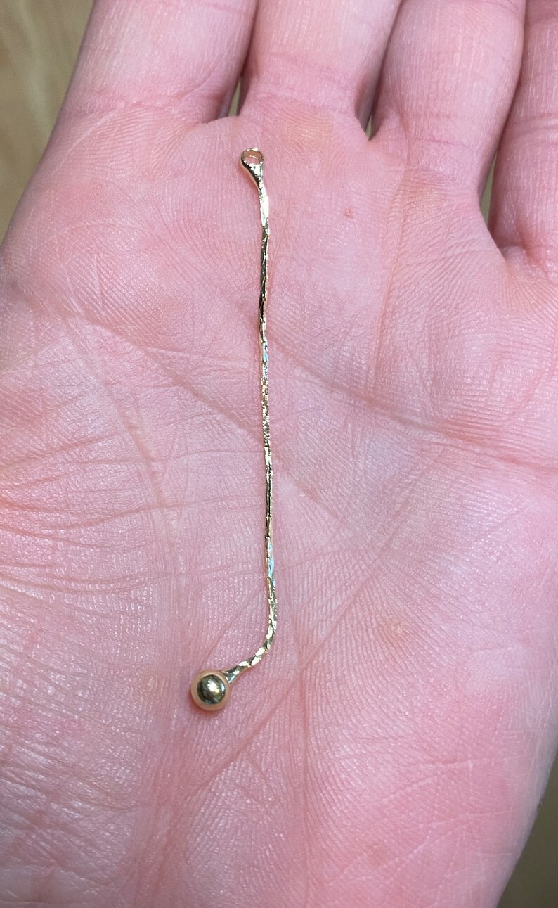 May include: A gold chain necklace with a small gold ball at the end.