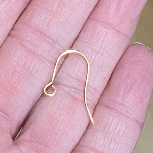May include: Gold earring hook, a type of jewelry finding used to attach earrings to a post.
