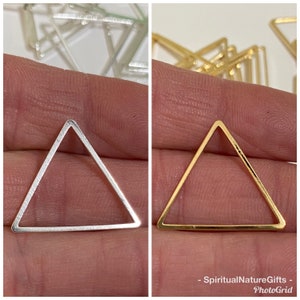 May include: Two triangle-shaped metal frames, one silver and one gold. The frames are open and can be used for crafting.