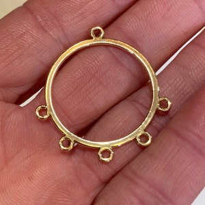 May include: A gold-toned metal jewelry connector component featuring a circular frame with five small, evenly spaced circular loops extending outward from the perimeter, designed for attaching multiple strands or charms in jewelry assembly.