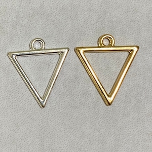 May include: Two triangle-shaped metal charms, one silver and one gold. Both charms have a loop at the top for attaching to a necklace or bracelet.