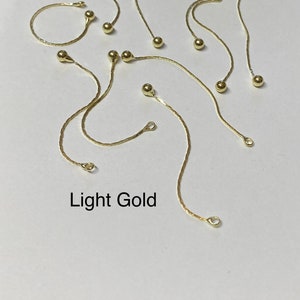 May include: A set of ten gold chain extenders with small round beads. The extenders are approximately 2 inches long. Light Gold.