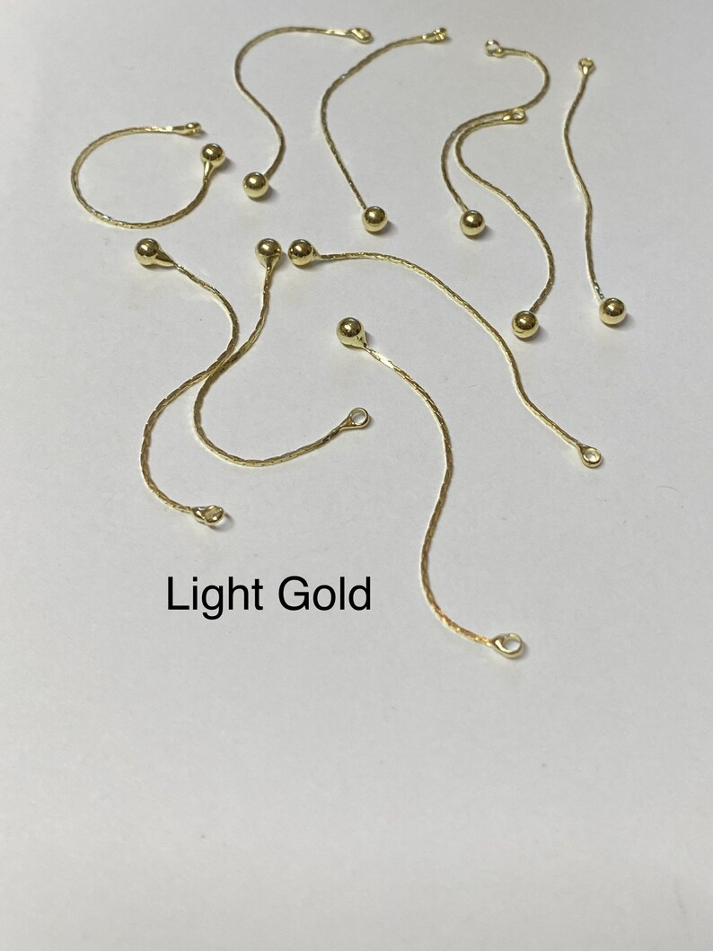May include: A set of ten gold chain extenders with small round beads. The extenders are approximately 2 inches long. Light Gold.