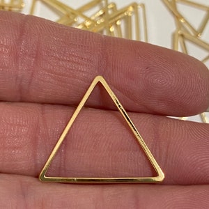 May include: A gold triangle-shaped metal frame. The frame is open and has a smooth, polished finish.