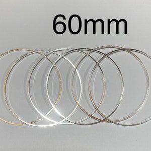 May include: Five silver metal hoops, each 60mm in diameter, stacked on top of each other.