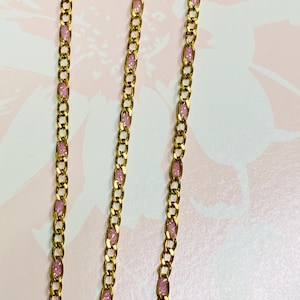 Puede incluir: Un collar de cadena de oro con detalles de esmalte rosa. La cadena es de estilo curb y el esmalte tiene forma rectangular.