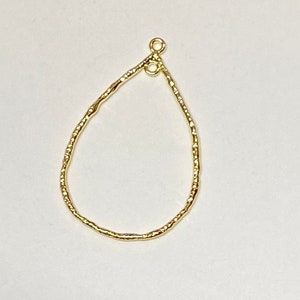 May include: Gold teardrop shaped earring finding with a textured surface.