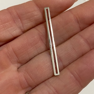 May include: A silver metal bar with two parallel lines running the length of the bar.
