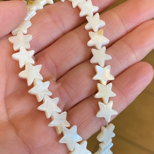 May include: A strand of white star-shaped beads made from mother of pearl.