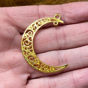 May include: Gold filigree crescent moon charm with a loop at the top for attaching to jewelry or other crafts.